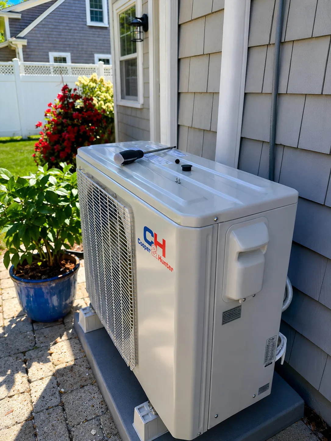 AI-enhanced image of a Cooper & Hunter outdoor mini-split unit beside shingle siding, associated with Durfee's Harwich installation